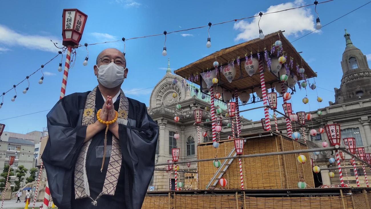 築地本願寺の境内に組まれた盆踊り用のやぐらの前で合掌する東森尚人副宗務長（撮影・寺沢卓）