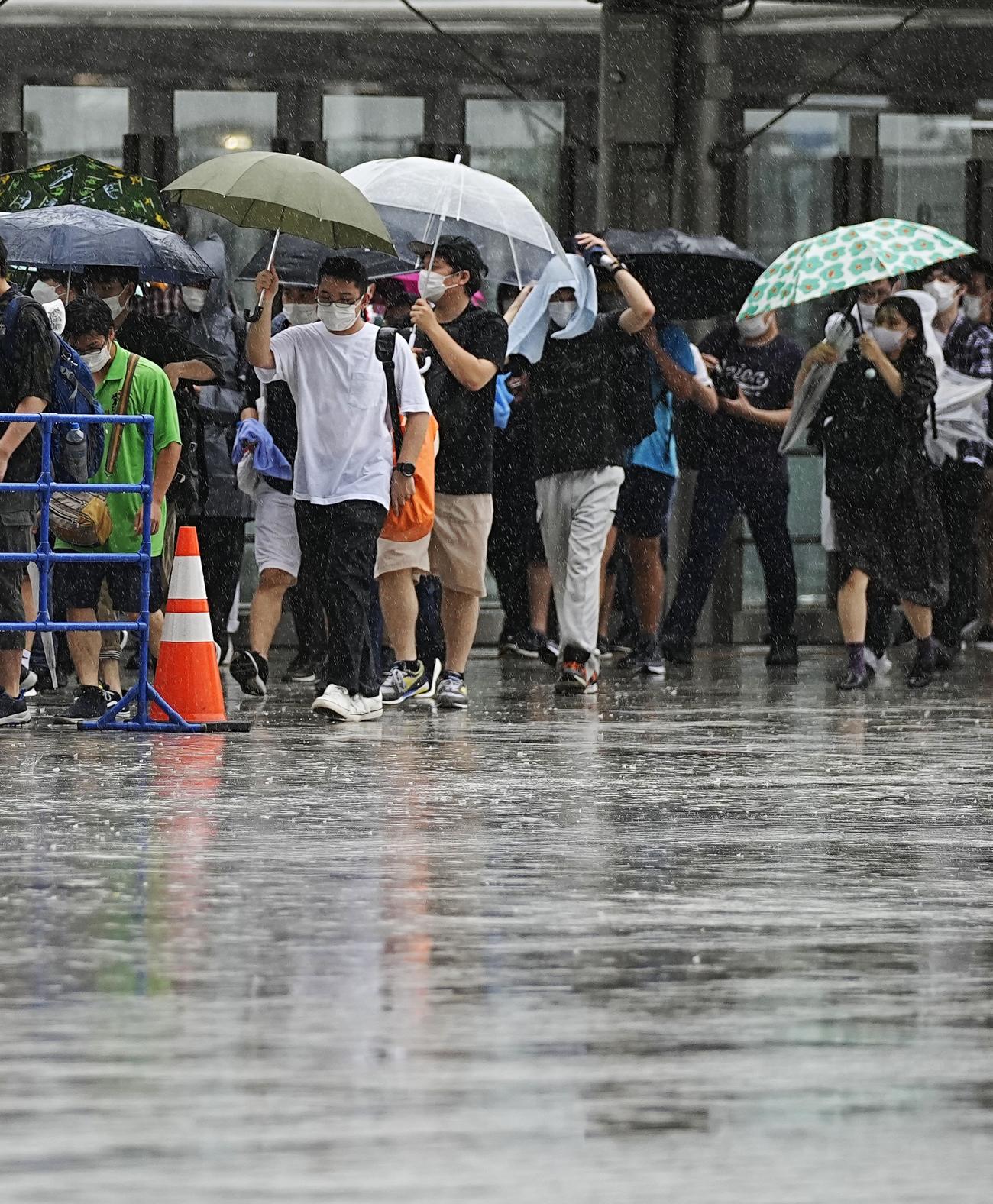 雨の中、東京ビッグサイトで開幕した同人誌即売会「コミックマーケット100」に向かう人たち（共同）