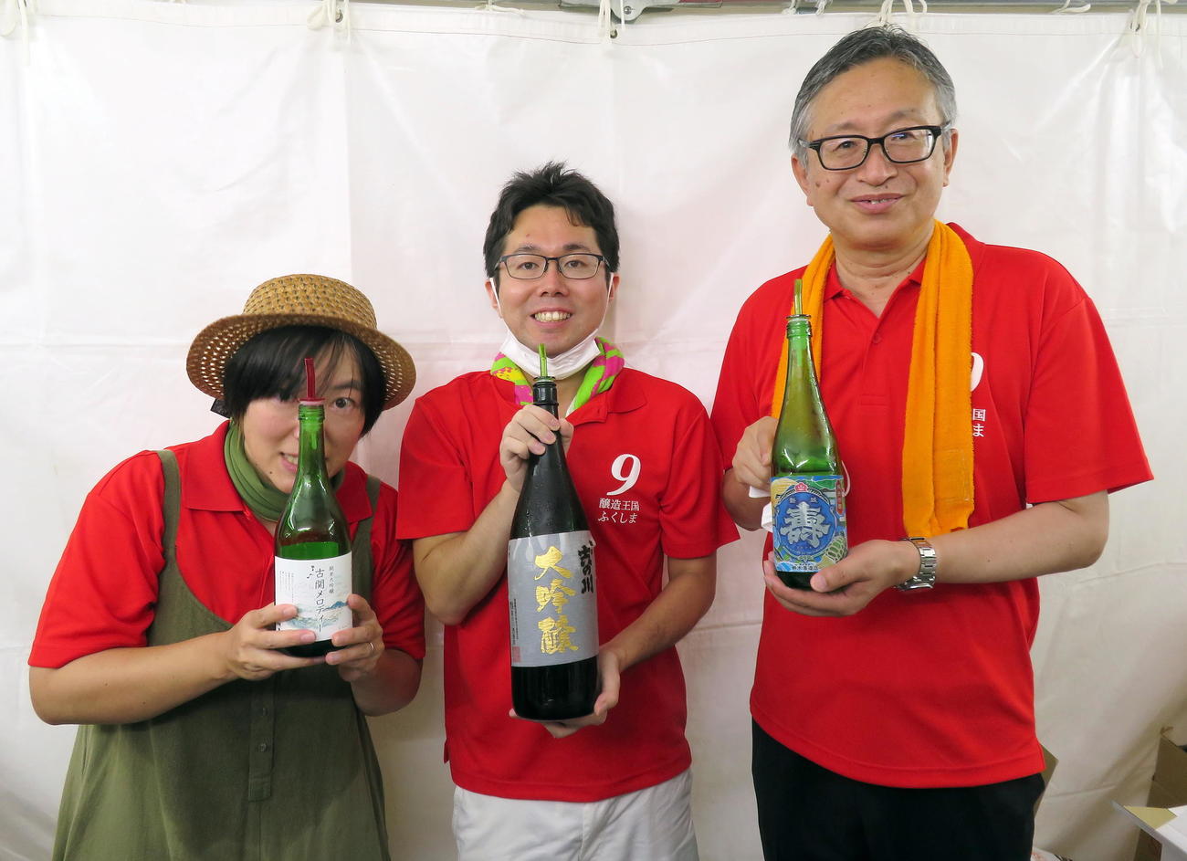鈴木酒造店の「磐城寿」を手に笑顔で酒を提供する福島県酒造組合の阿部淳専務理事（右端）ら担当者たち（撮影・鎌田直秀）