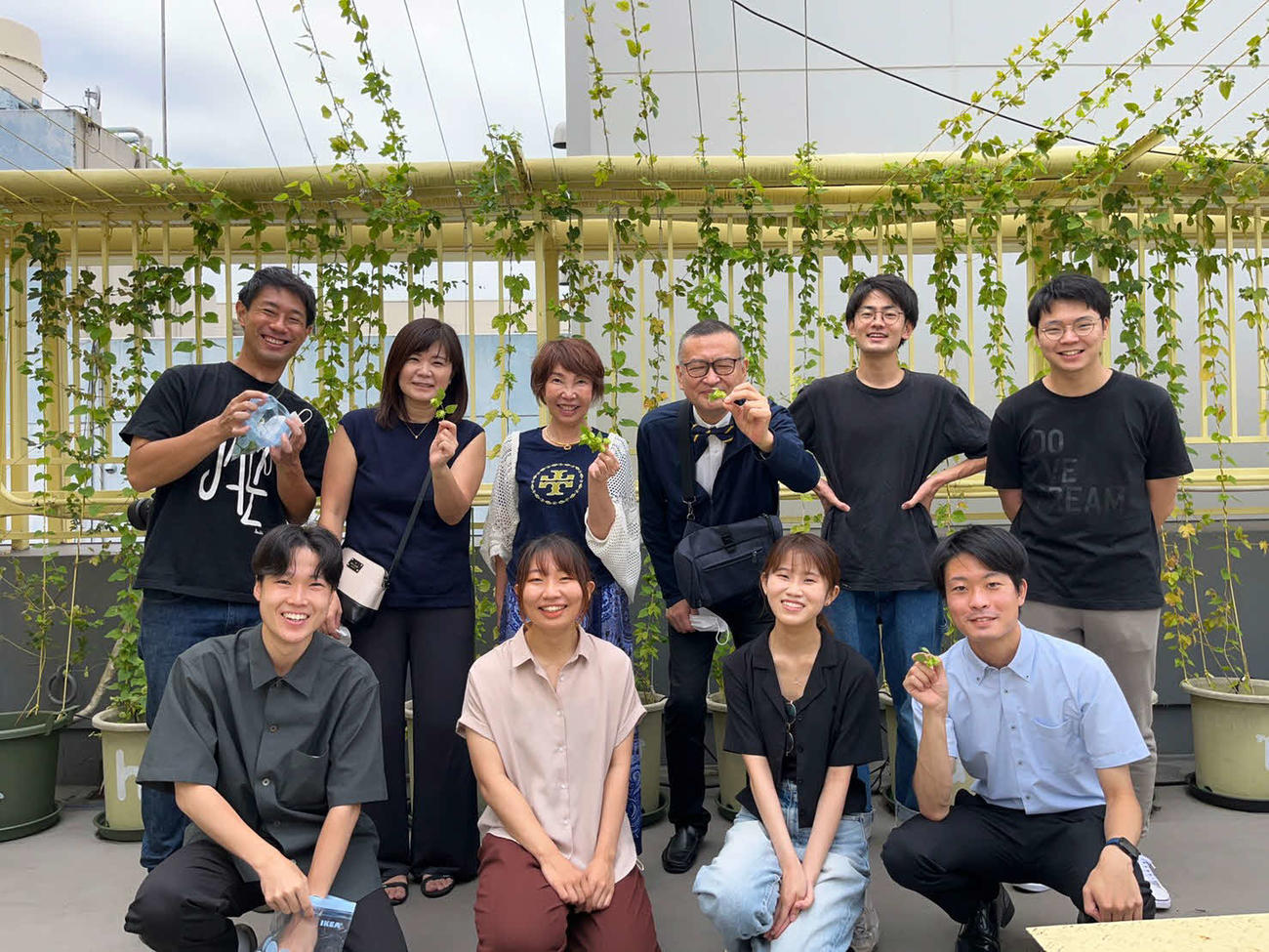 雑居ビルの屋上で採れたホップを手に笑顔を見せる東大生と商店会の関係者ら（永野真義氏提供）