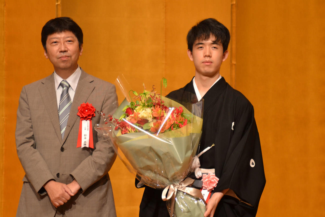 師匠の杉本昌隆八段（左）から贈呈された花束を手にする藤井聡太棋聖（右）