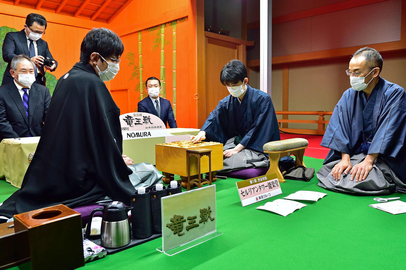 竜王戦7番勝負第1局2日目は藤井聡太竜王（中央）が初日の封じ手を開封して再開（左は挑戦者の広瀬章人八段、右は立会人の島朗九段、日本将棋連盟提供）