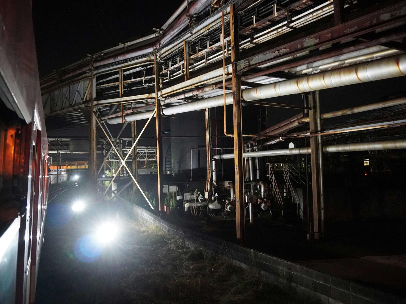 岳南原田－比奈駅間でライトアップされた工場のパイプラインの下をくぐる（撮影・井上学）