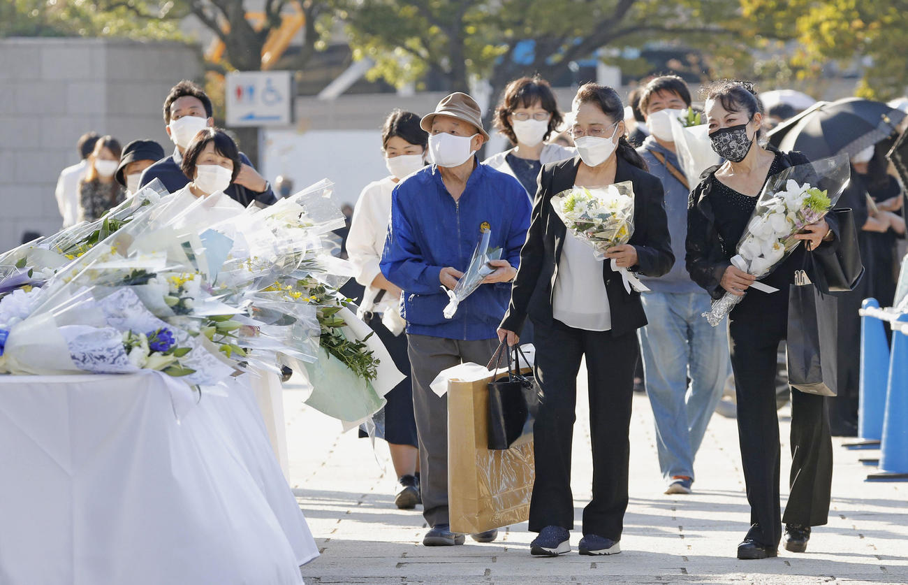 安倍元首相の県民葬会場を訪れ、外に設置された献花台に花を手向ける人たち（共同）