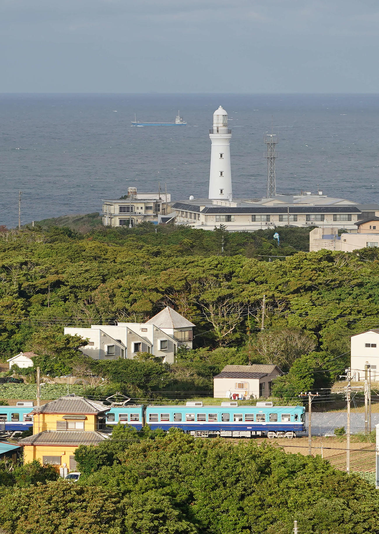 高台で2時間ほど粘ったところ、犬吠埼灯台の奥に船が見えるタイミングで電車が！雲の合間から光が差したのも良かった（撮影・河野匠）