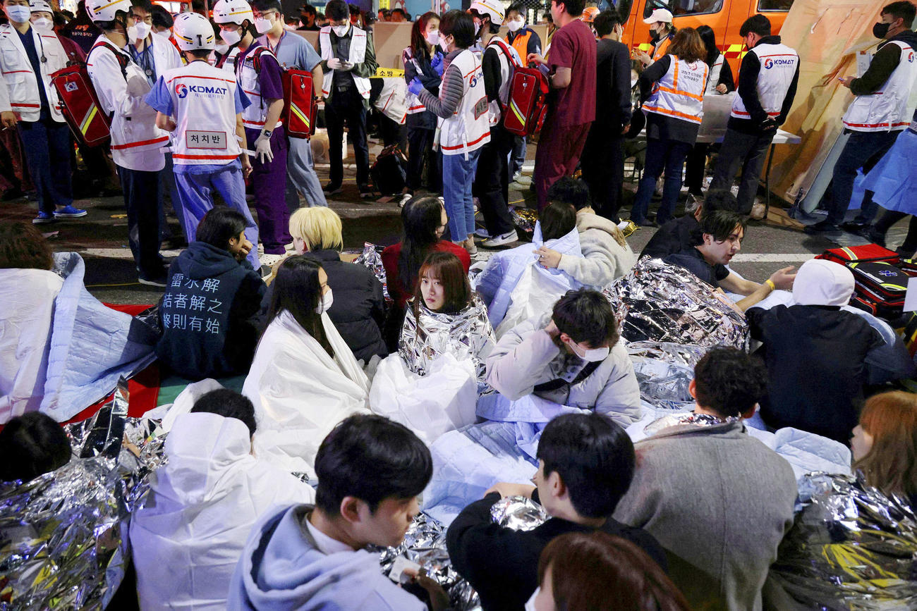 ソウルの繁華街・梨泰院で発生した事故で、救助され座り込む負傷者ら＝30日（ロイター＝共同）