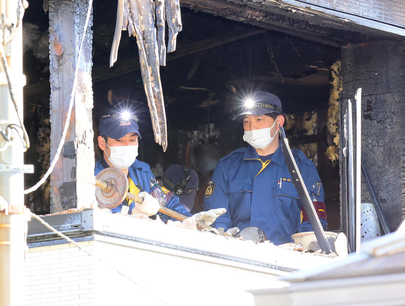 火災があった世田谷区成城の村田さんの住宅2階部分からバーベルを運ぶ警視庁の捜査員（撮影・足立雅史）