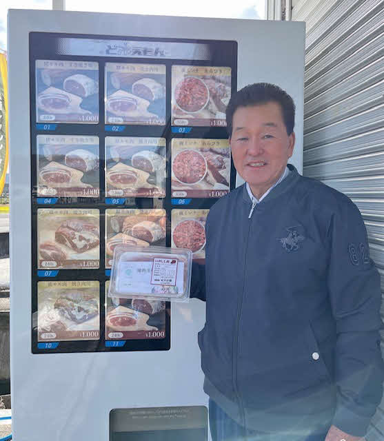 ジビエの肉の自動販売機の前で笑顔を見せる「いの屋」の北浦順嗣店主（本人提供）