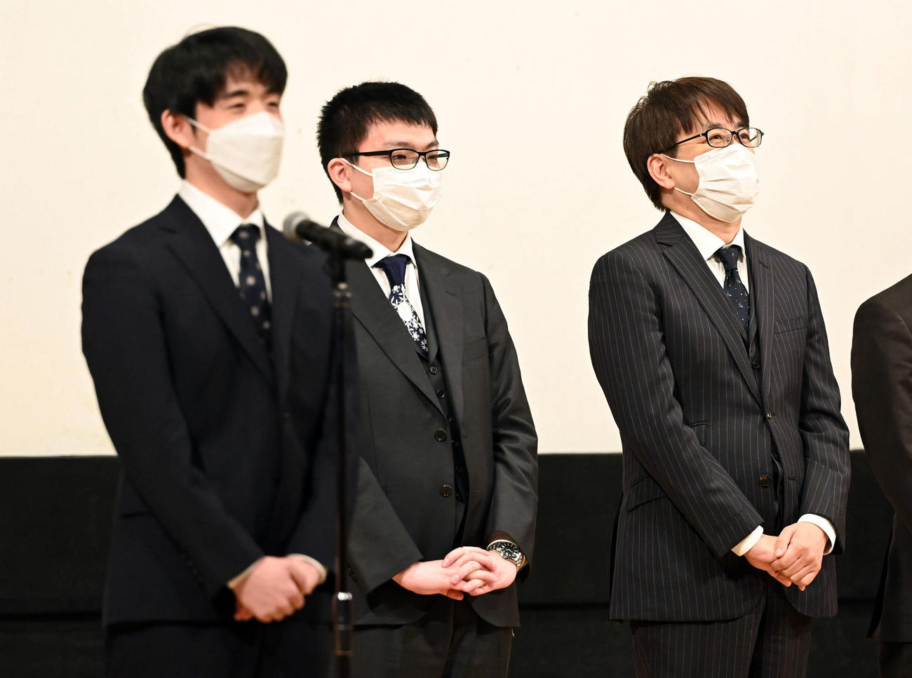 開会式であいさつをする西軍の藤井竜王（左）に笑顔を見せる東軍の羽生九段。中央は東軍の永瀬王座（撮影・たえ見朱実）