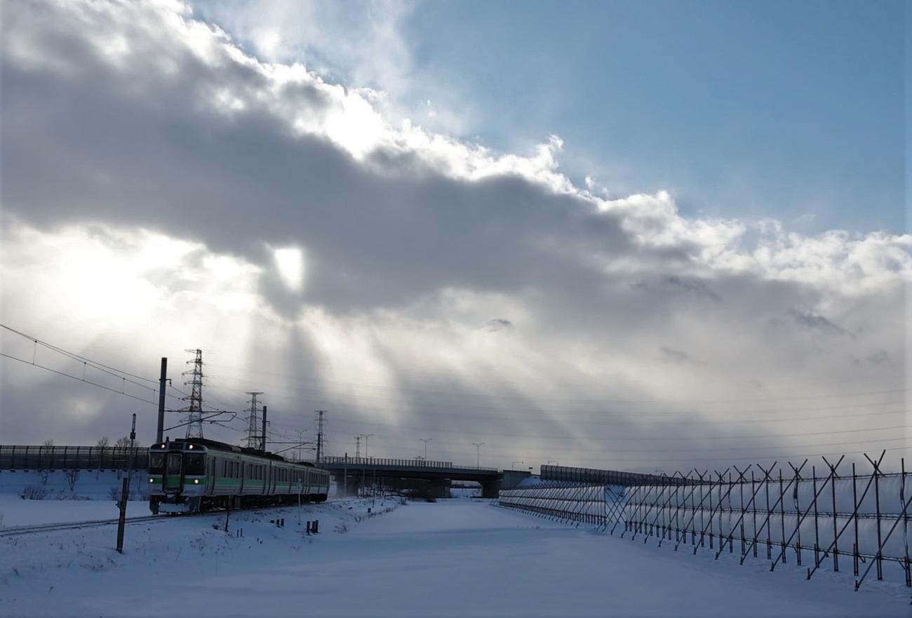 雪雲の合間からさす光を背に走る列車（撮影・黒川智章）