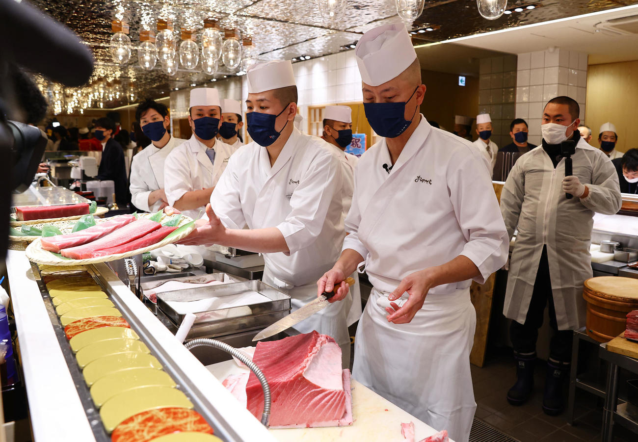 店内に運ばれた一番マグロを手際よくさばく、おのでら坂上暁史料理長（手前）ら（撮影・垰建太）