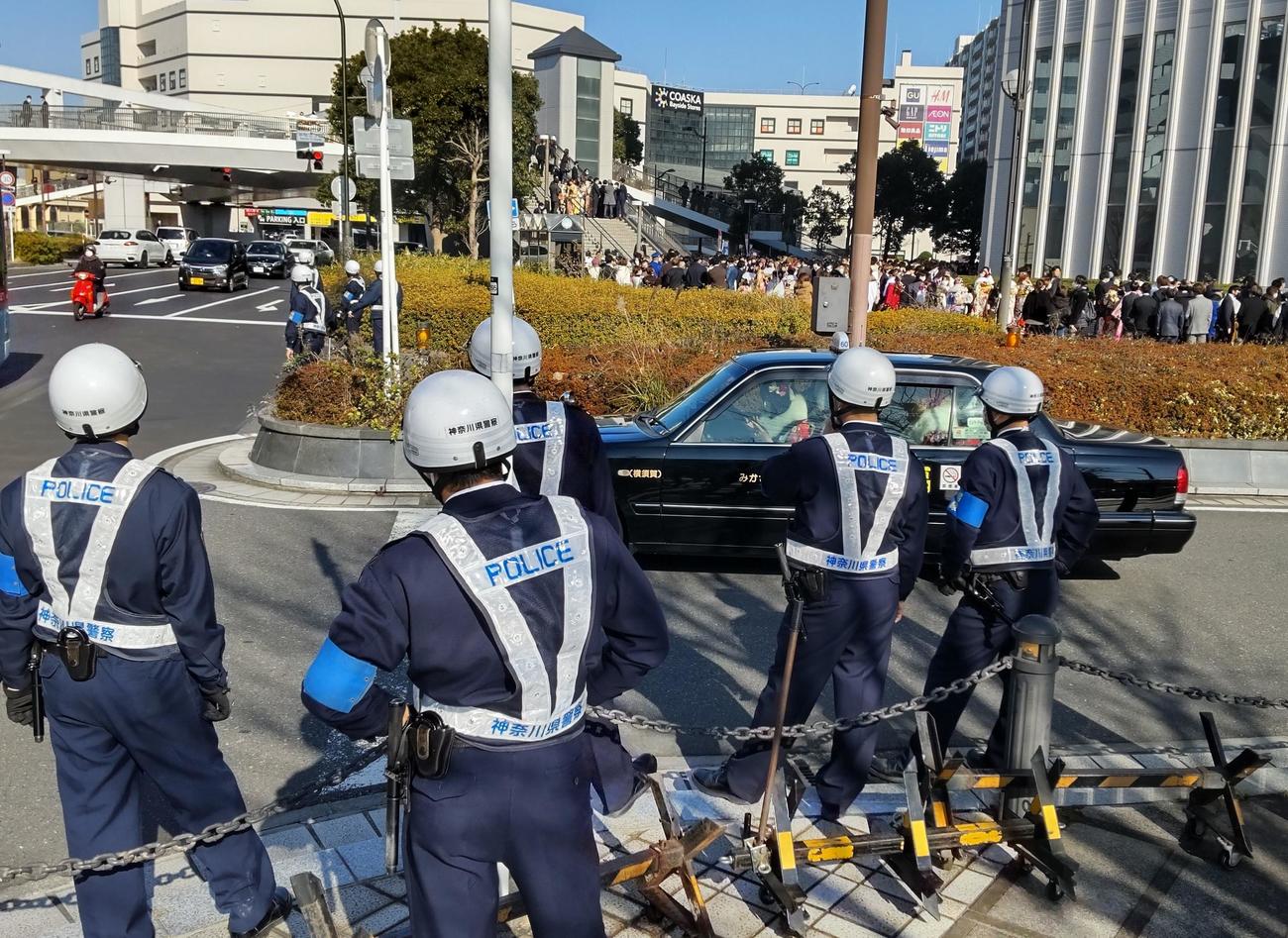 京急汐入駅前のバスとタクシー専用のロータリーには複数の制服警察官が配備された。通り過ぎるタクシーには晴れ着の女性が乗り込み、植え込みの向こうには新成人が歓談していた（撮影・寺沢卓）