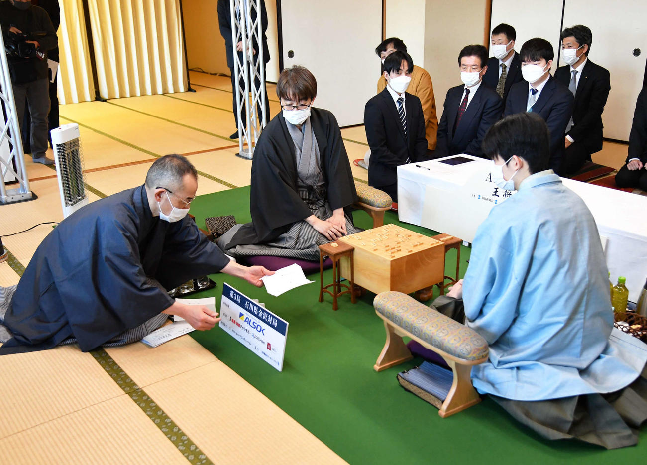 立会人の島朗九段（左）が開封した封じ手を見る羽生善治九段（中央）と藤井聡太王将（右）（代表撮影）