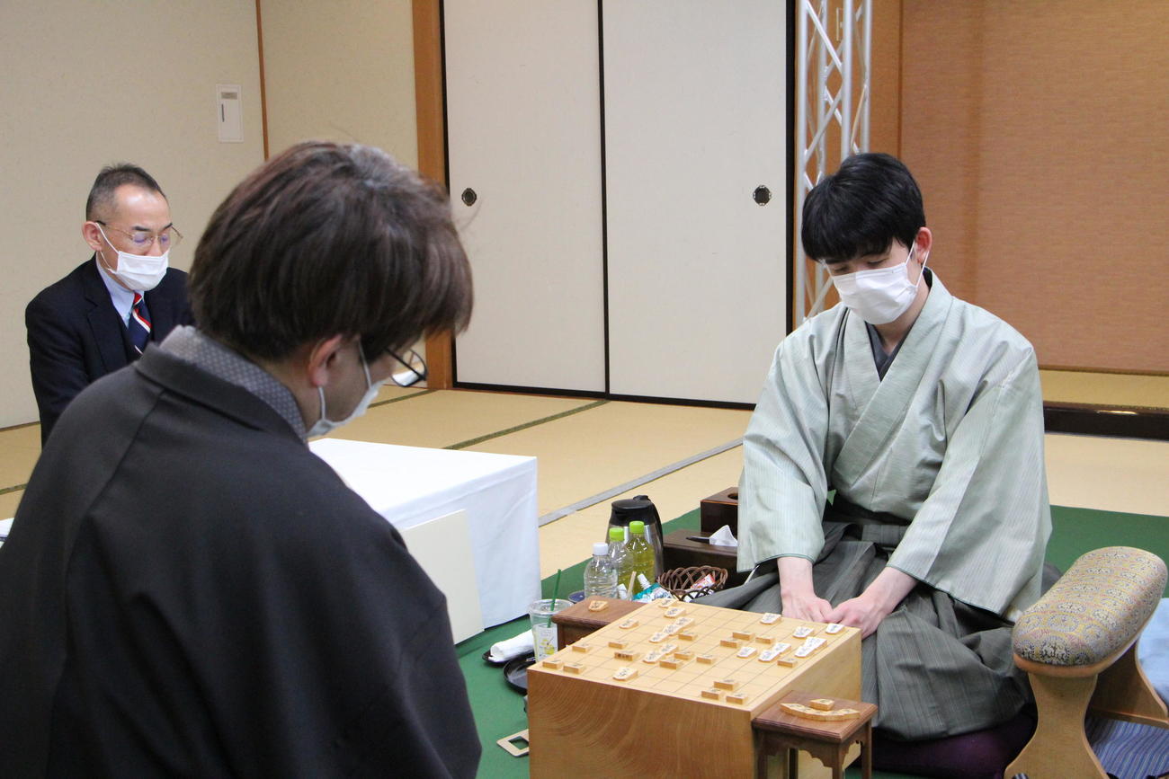 終局後、インタビューに応じる藤井聡太王将。手前は羽生善治九段（日本将棋連盟提供）