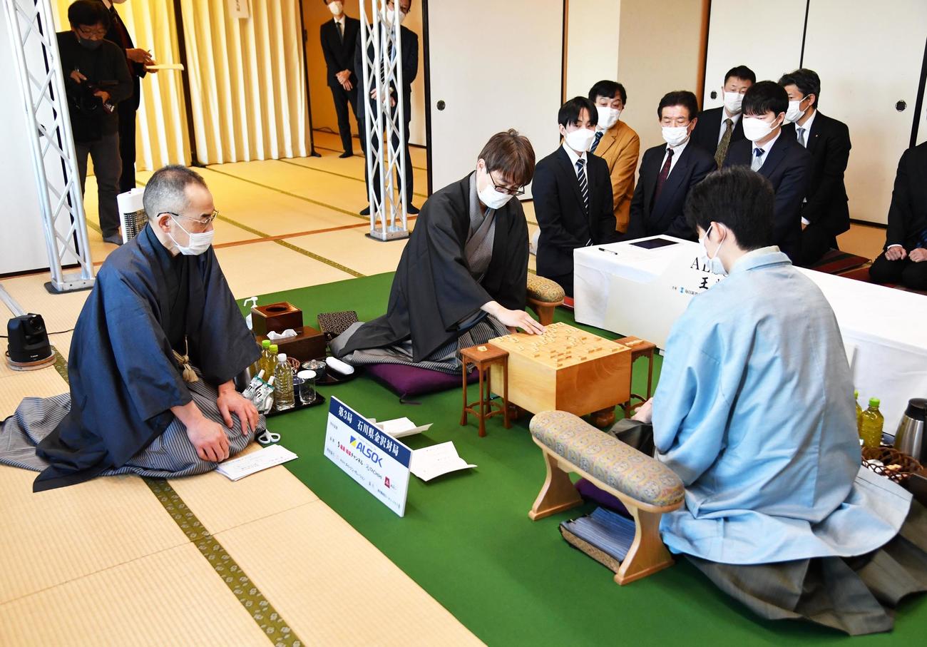 封じ手を指す挑戦者の羽生善治九段（中央）。左は立会の島朗九段。右は藤井聡太王将（代表撮影）