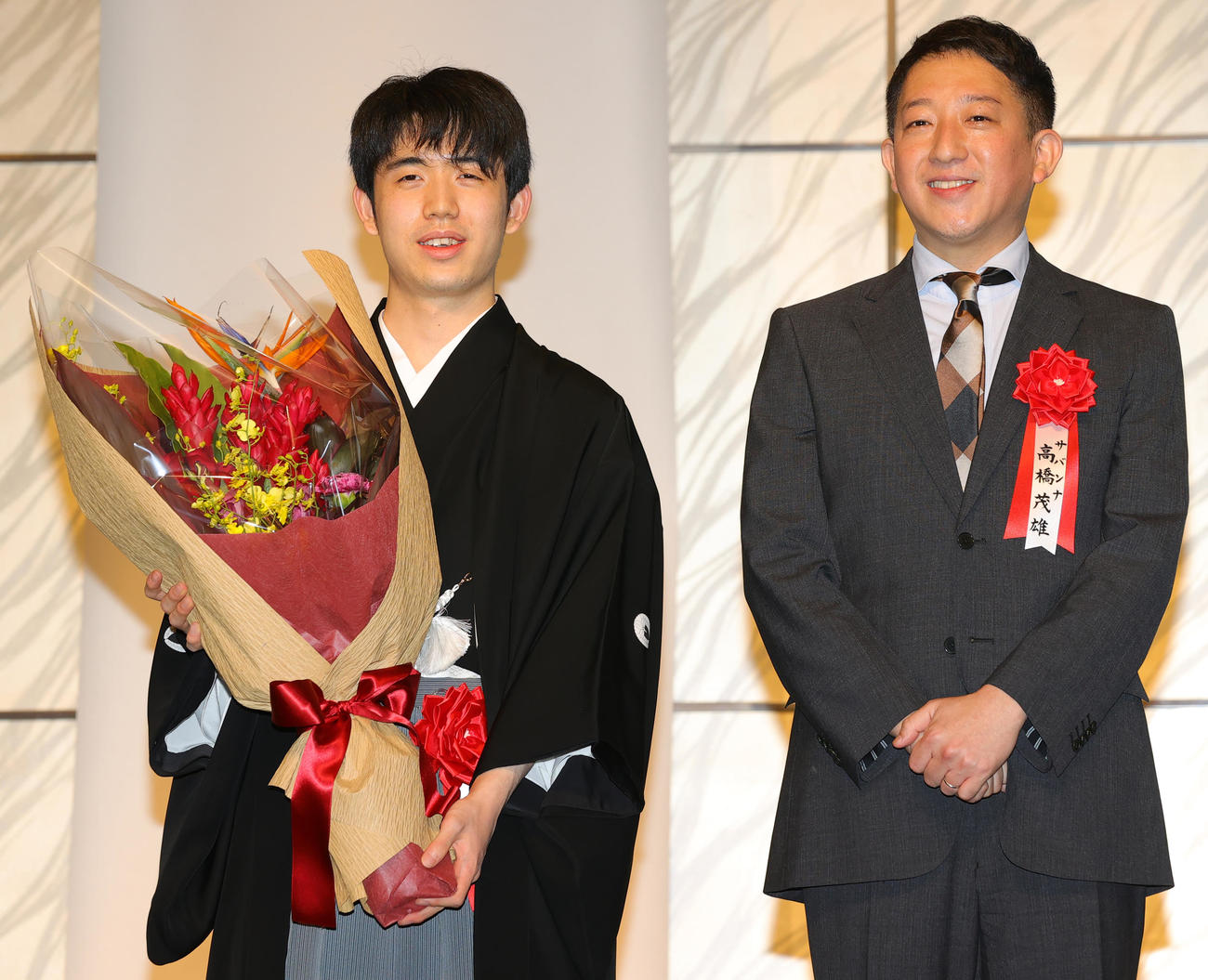 第35期竜王就位式で、サバンナ高橋茂雄（右）から花束を受け取り笑顔の藤井竜王（撮影・野上伸悟）