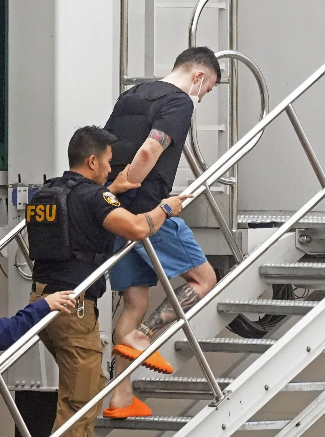 フィリピン・マニラの国際空港で、強制送還のため航空機に乗せられる藤田聖也容疑者（右）（共同）