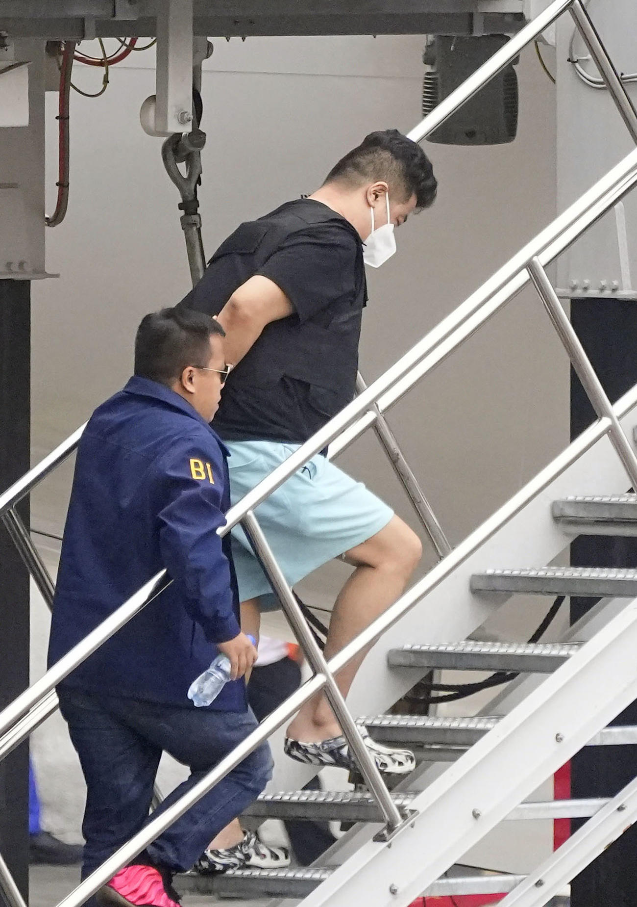フィリピン・マニラの国際空港で、強制送還のため航空機に乗せられる今村磨人容疑者（右）（共同）