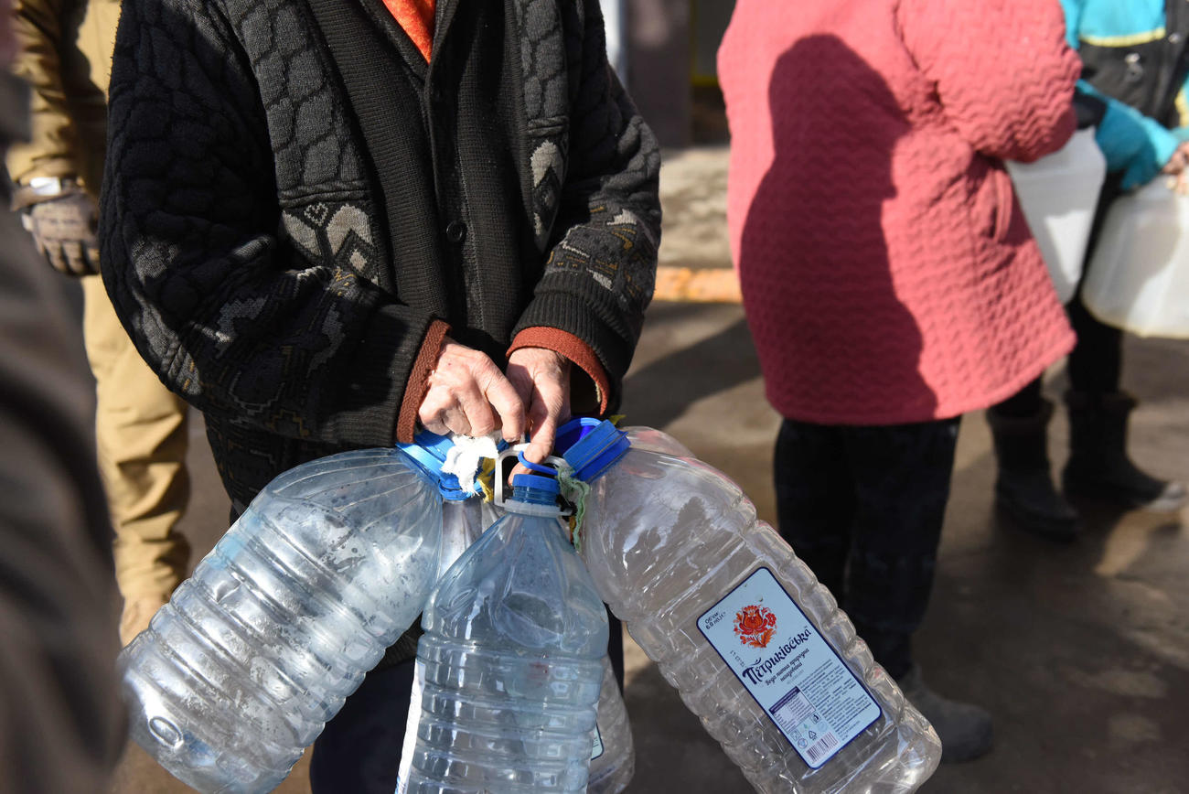 いくつもの大きなペットボトルをいくつも持ち給水を待つ人たち（武馬怜子氏撮影）