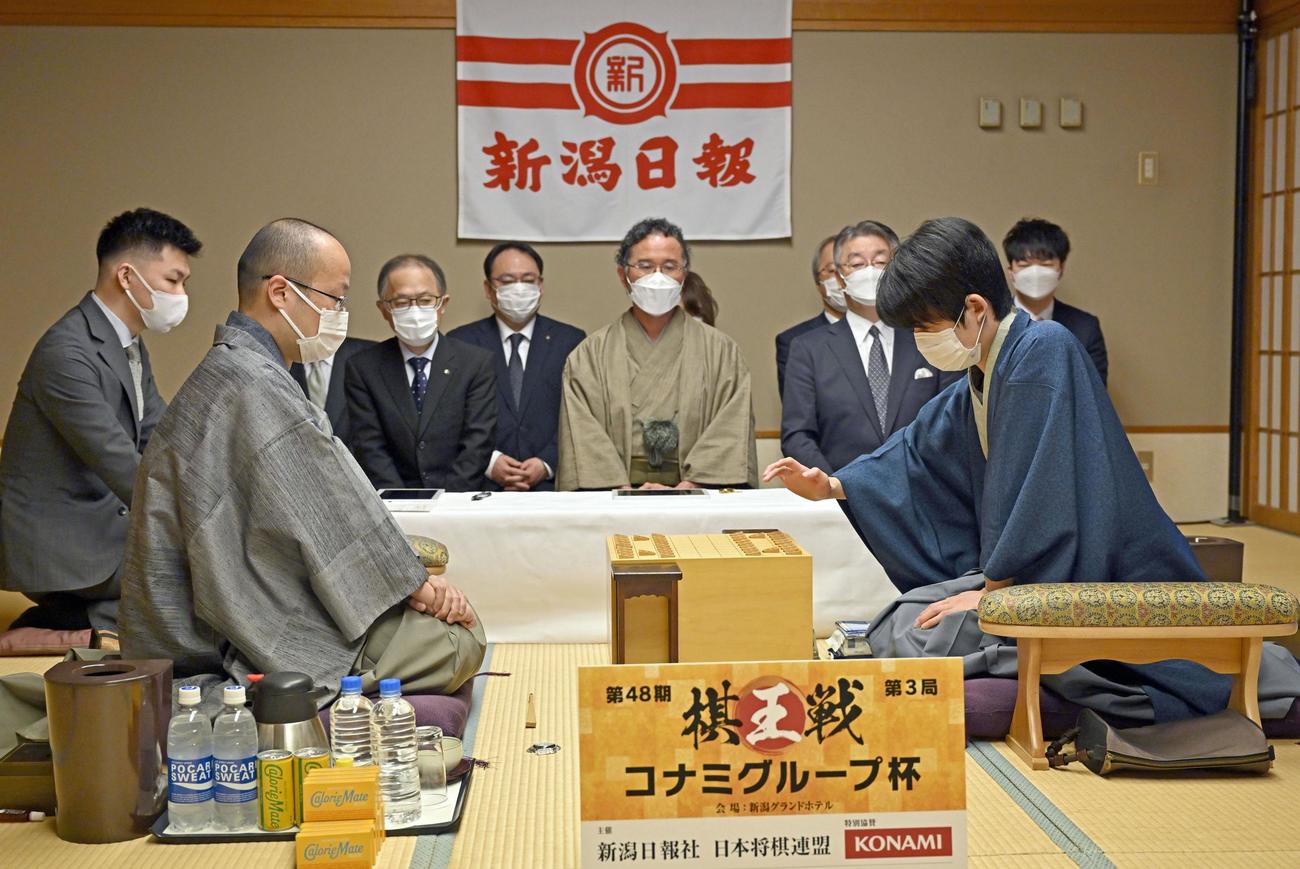 第48期棋王戦コナミグループ杯5番勝負第3局で、初手を指す藤井聡太五冠（右）と、渡辺明棋王（代表撮影）