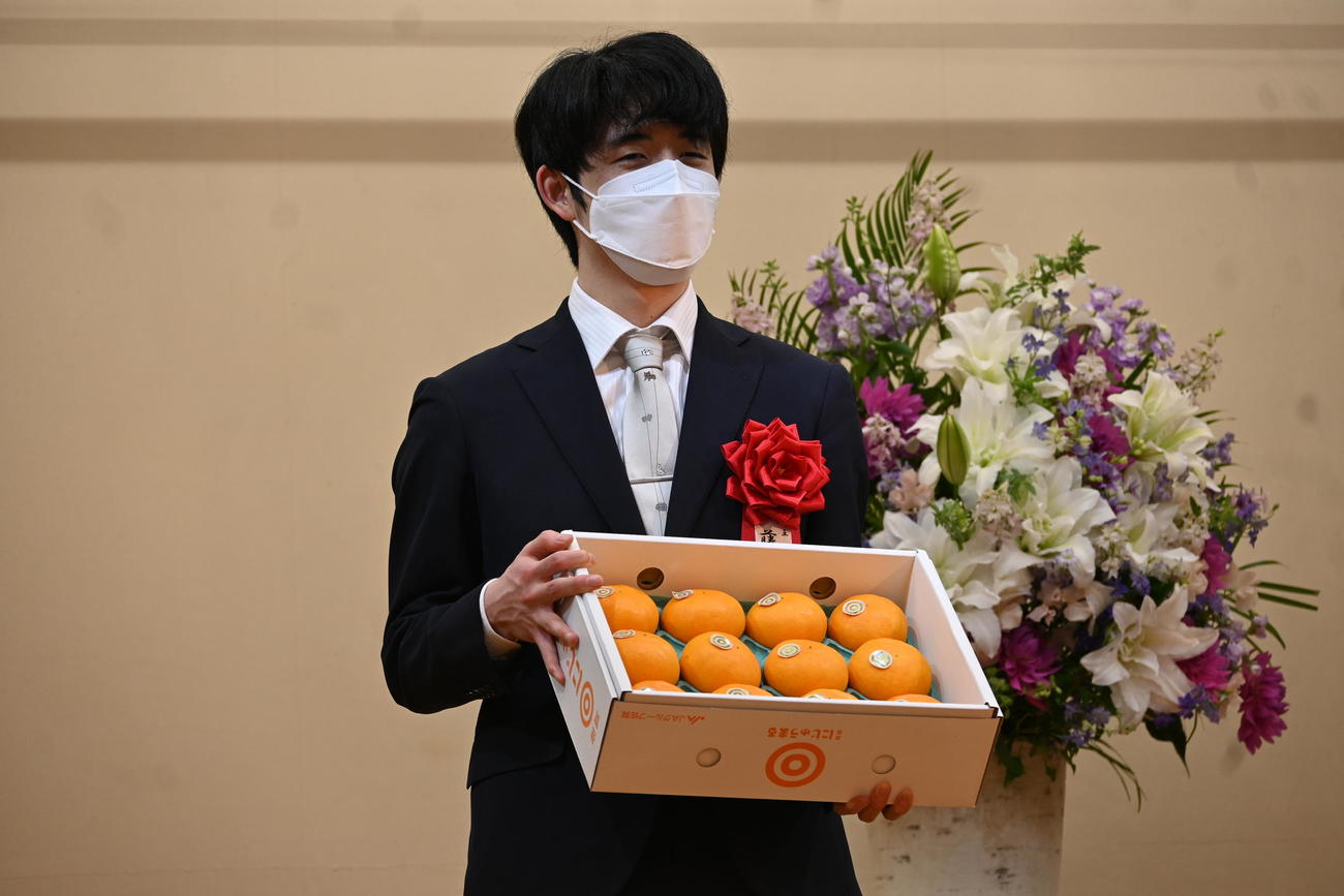 第72期ALSOK杯王将戦7番勝負第6局の前夜祭で佐賀県上峰町名産のミカンを贈られた藤井聡太王将（撮影・松浦隆司）