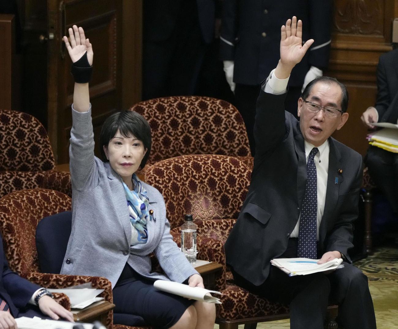 参院予算委で答弁のため挙手する、高市経済安保相（左）と松本総務相（共同）