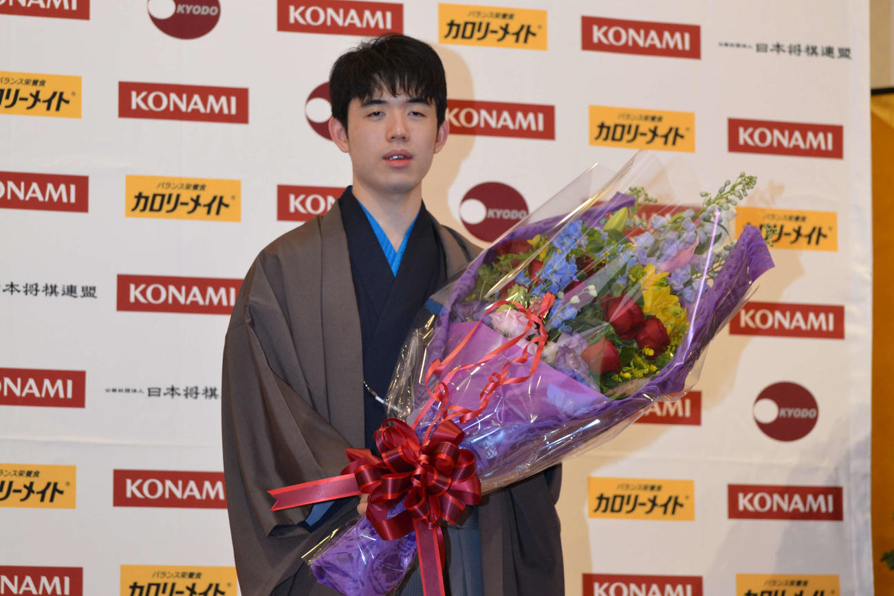 記者会見で花束を手にする藤井聡太棋王