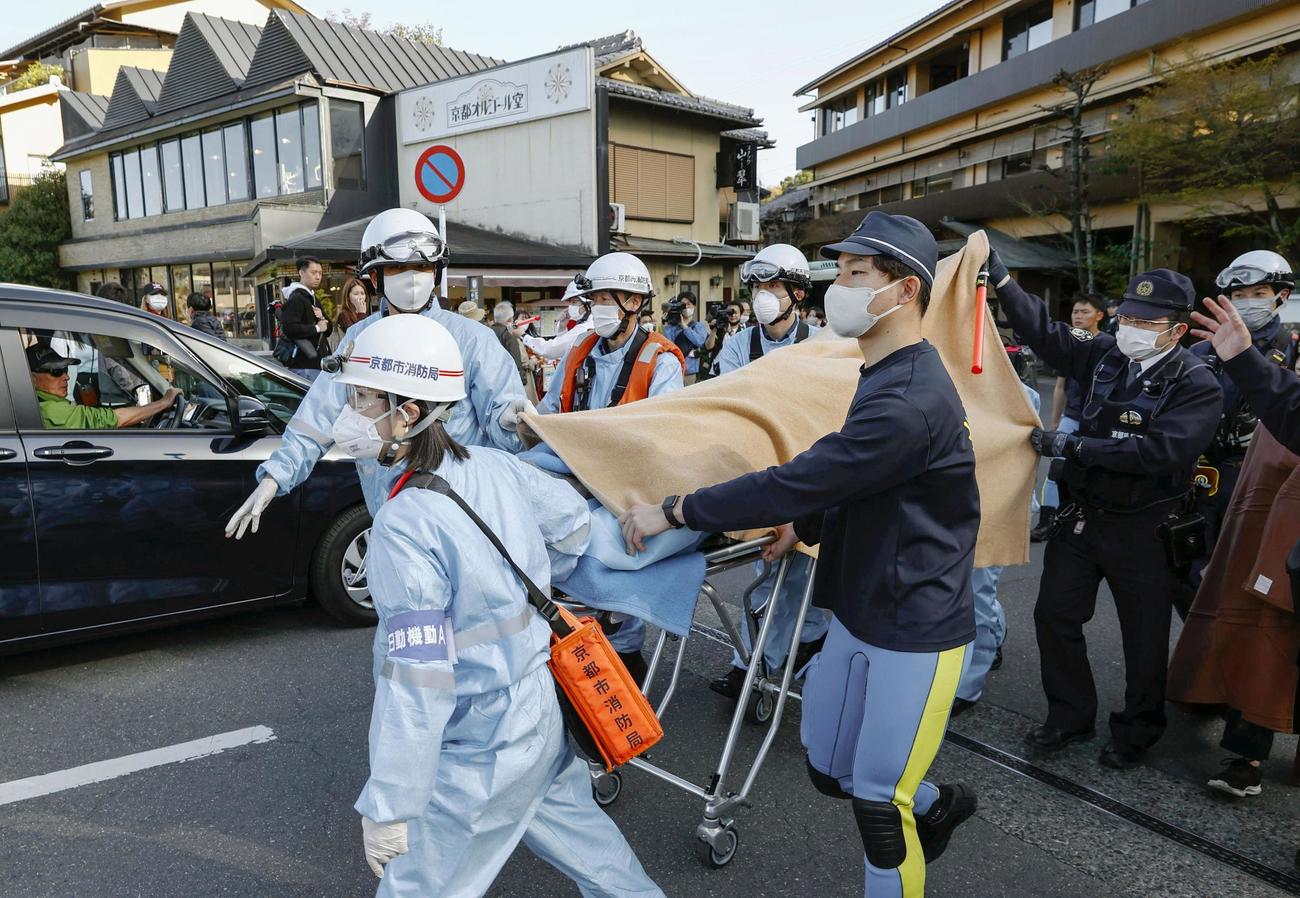 京都・嵐山の下船場所に到着した人を担架に乗せ、搬送する消防局員ら（共同）