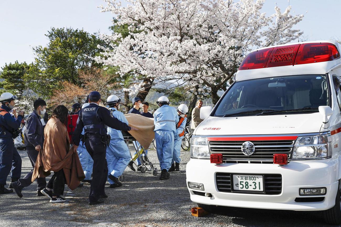 京都・嵐山の下船場所に到着した人を担架に乗せ、搬送する消防局員ら（共同）