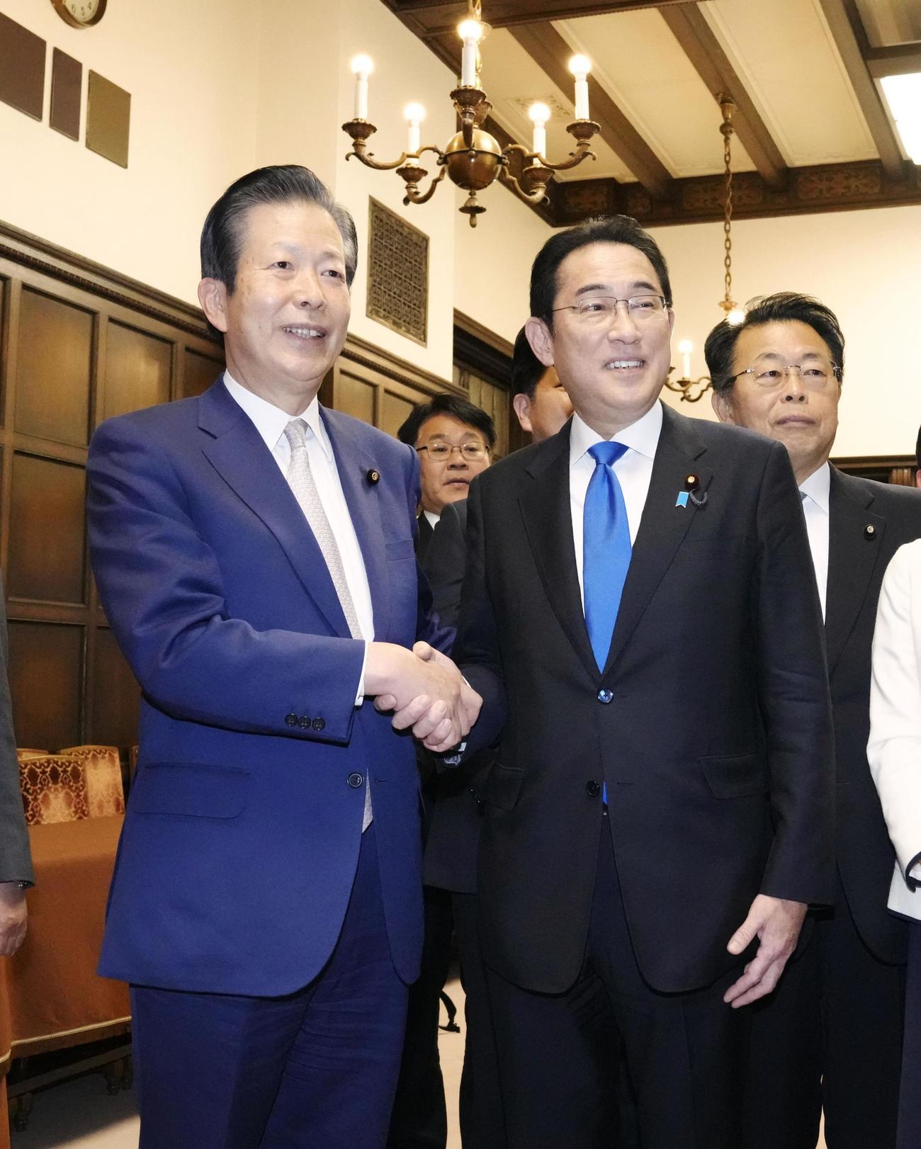2023年度予算が成立し、公明党の山口代表（左）と握手する岸田首相（共同）