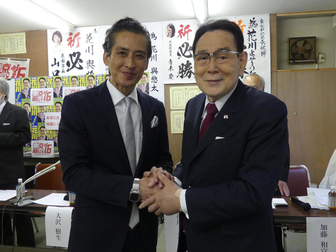 北区長選で選挙協力することになり、握手をかわす大沢樹生氏（左）と花川与惣太区長（撮影・中山知子）