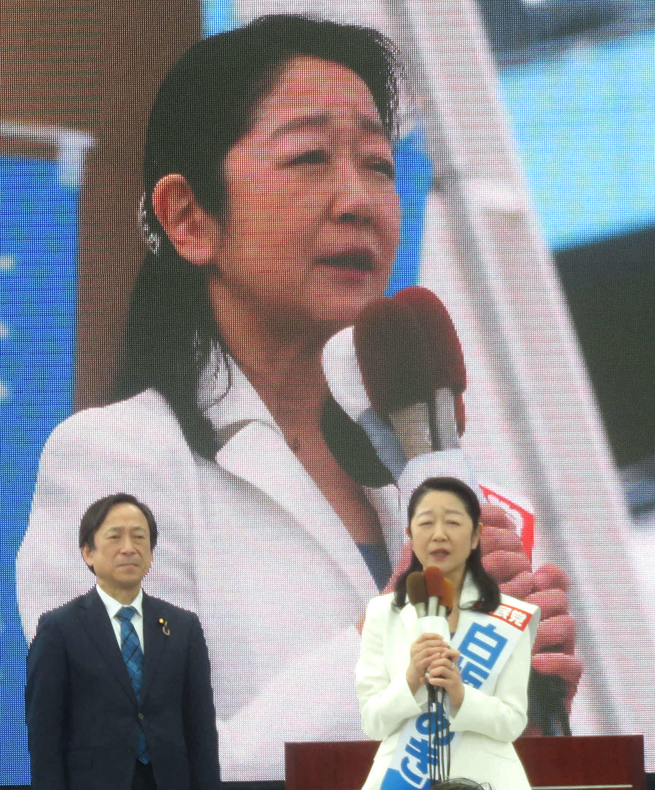 自民党公認の新人白坂亜紀氏（右）は大型スクリーンをバックに第一声を行った（撮影・大上悟）