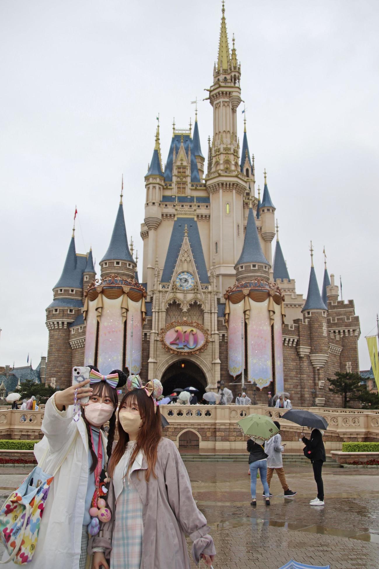 開業40周年を迎えた東京ディズニーランドのシンデレラ城前で写真に納まる来園者（共同）