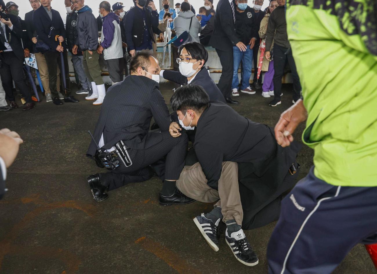 岸田首相が衆院和歌山1区補欠選挙の応援演説に訪れた和歌山市の雑賀崎漁港で、発煙筒のようなものを投げ込んだ男を取り押さえる人たち（共同）