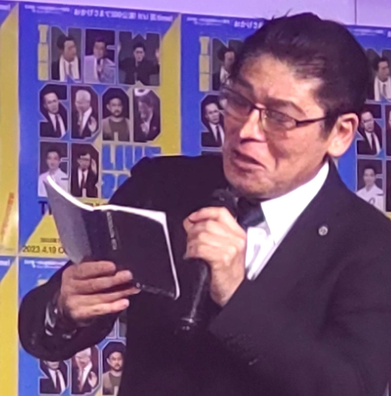 背広の内ポケットから取り出した手帳を読み上げる「キシダ総理」役の浜田太一（撮影・寺沢卓）