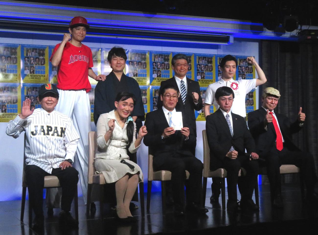 ザ・ニュースペーパーのメンバー9人。前列左から竹内康明（クリヤマ監督）、山本天心（えりあるふぃや）、浜田太一（キシダ総理）、福本ヒデ（吉田シンジ）、松下あきら（とらんぷ前大統領）、後列左から石坂タケシ（大谷ショウヘイ）、土谷ひろし（藤井ソウタ）、田中カツノリ（ババ代表）、田中学（ヨシムラ府知事）（撮影・寺沢卓）