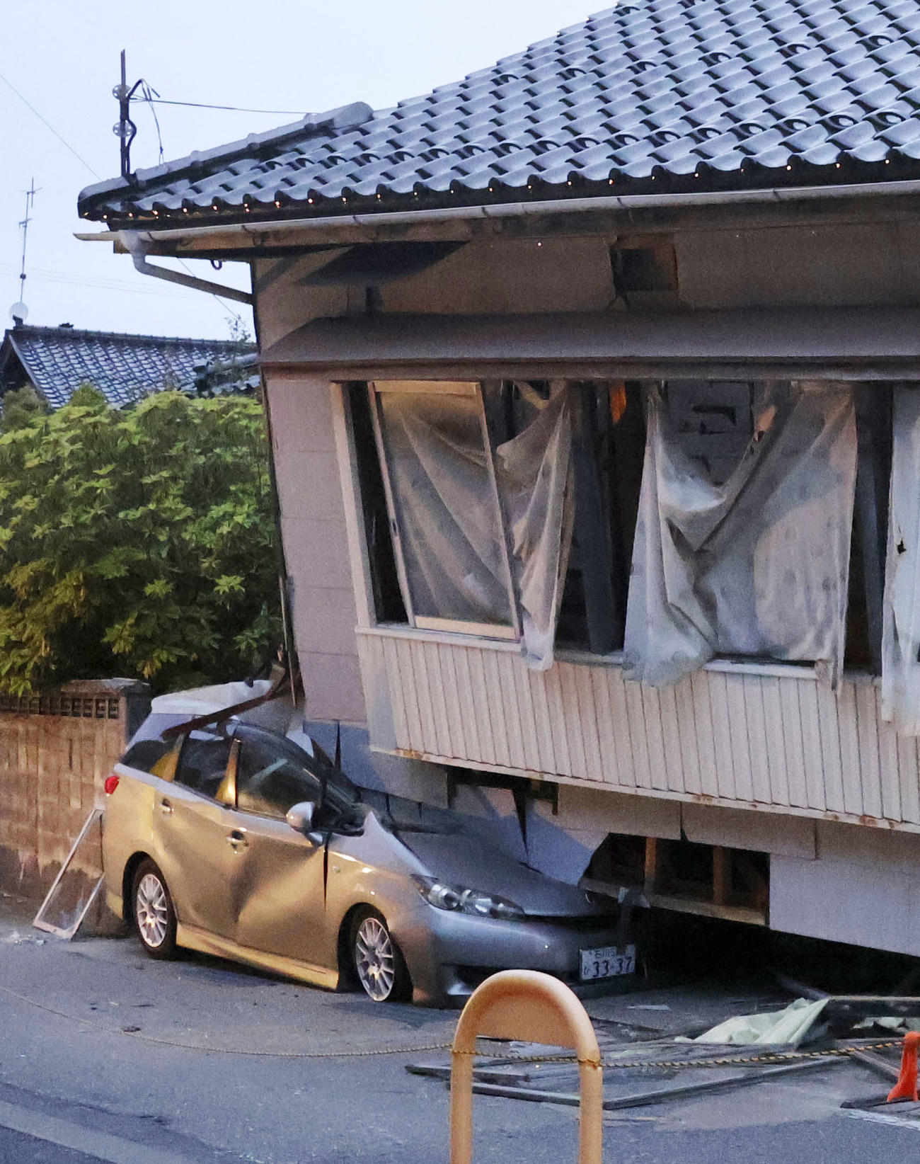 震度6強の地震で倒壊した民家に押しつぶされた車（共同）