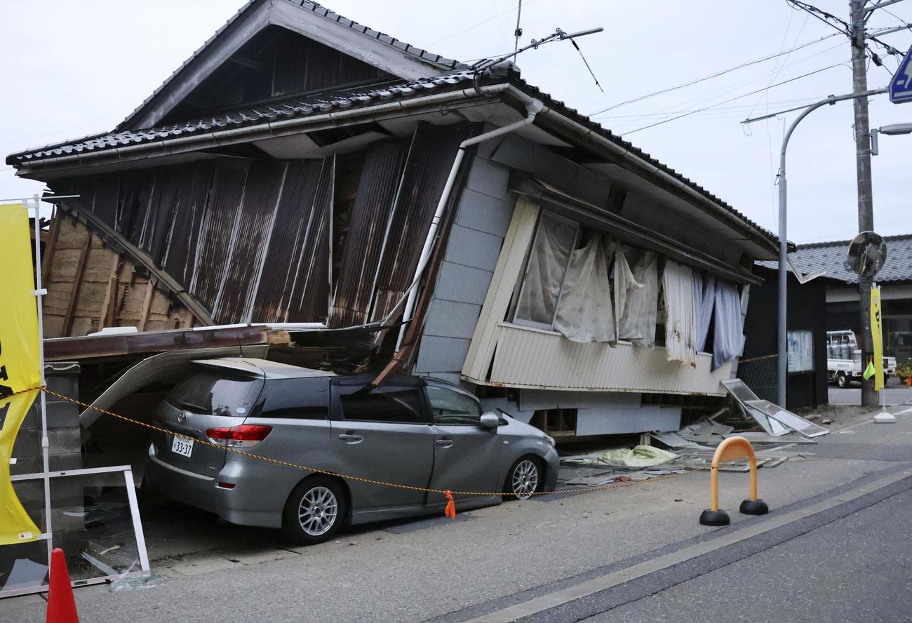 震度6強の地震で倒壊し、車を押しつぶした民家（共同）
