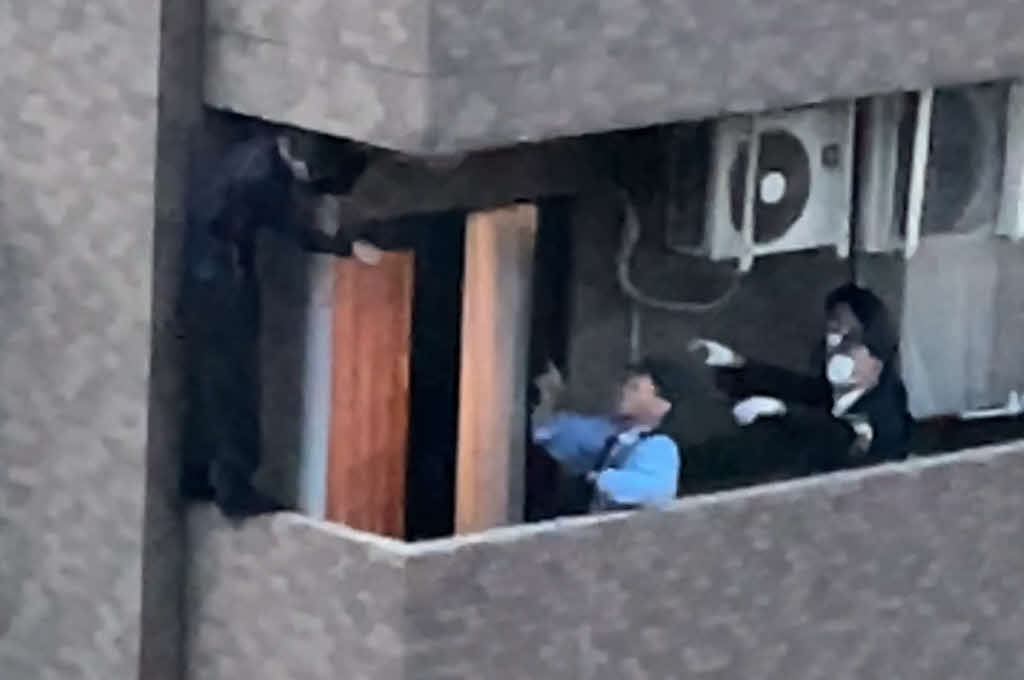 東京・赤坂のマンションで警察官に確保される男（左）（目撃者提供）