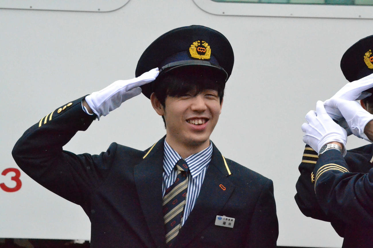 三陸鉄道の車両を前に笑顔で敬礼する藤井聡太叡王