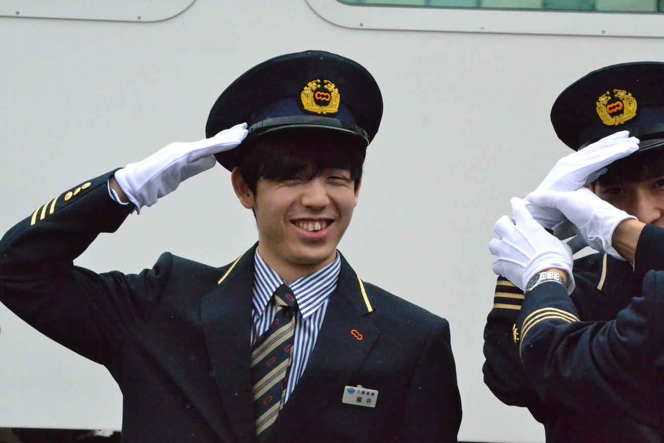 三陸鉄道の車両を前に笑顔で敬礼する藤井聡太叡王