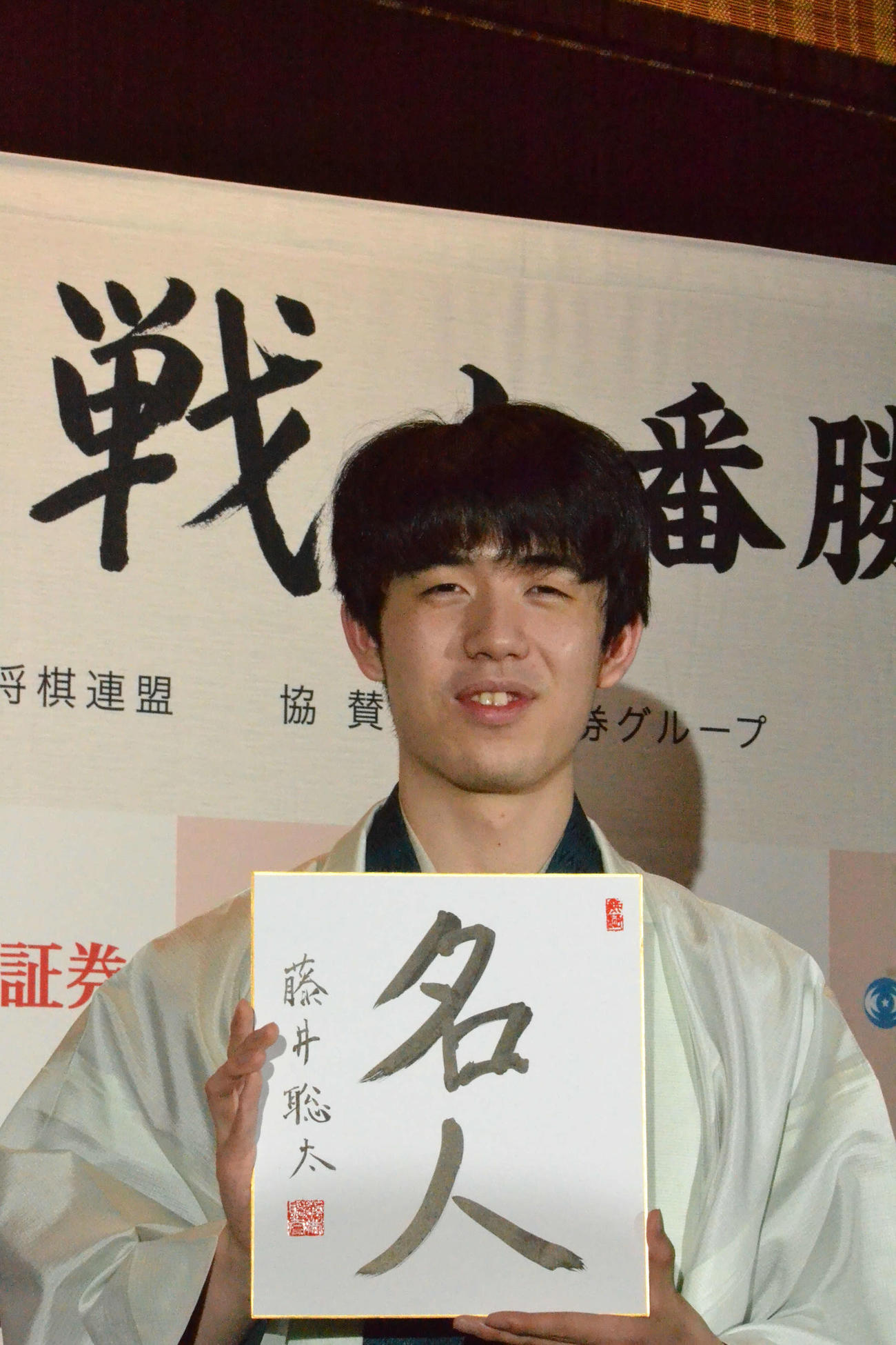 初仕事として「名人」と揮毫（きごう）した色紙を手に撮影に応じる藤井聡太新名人