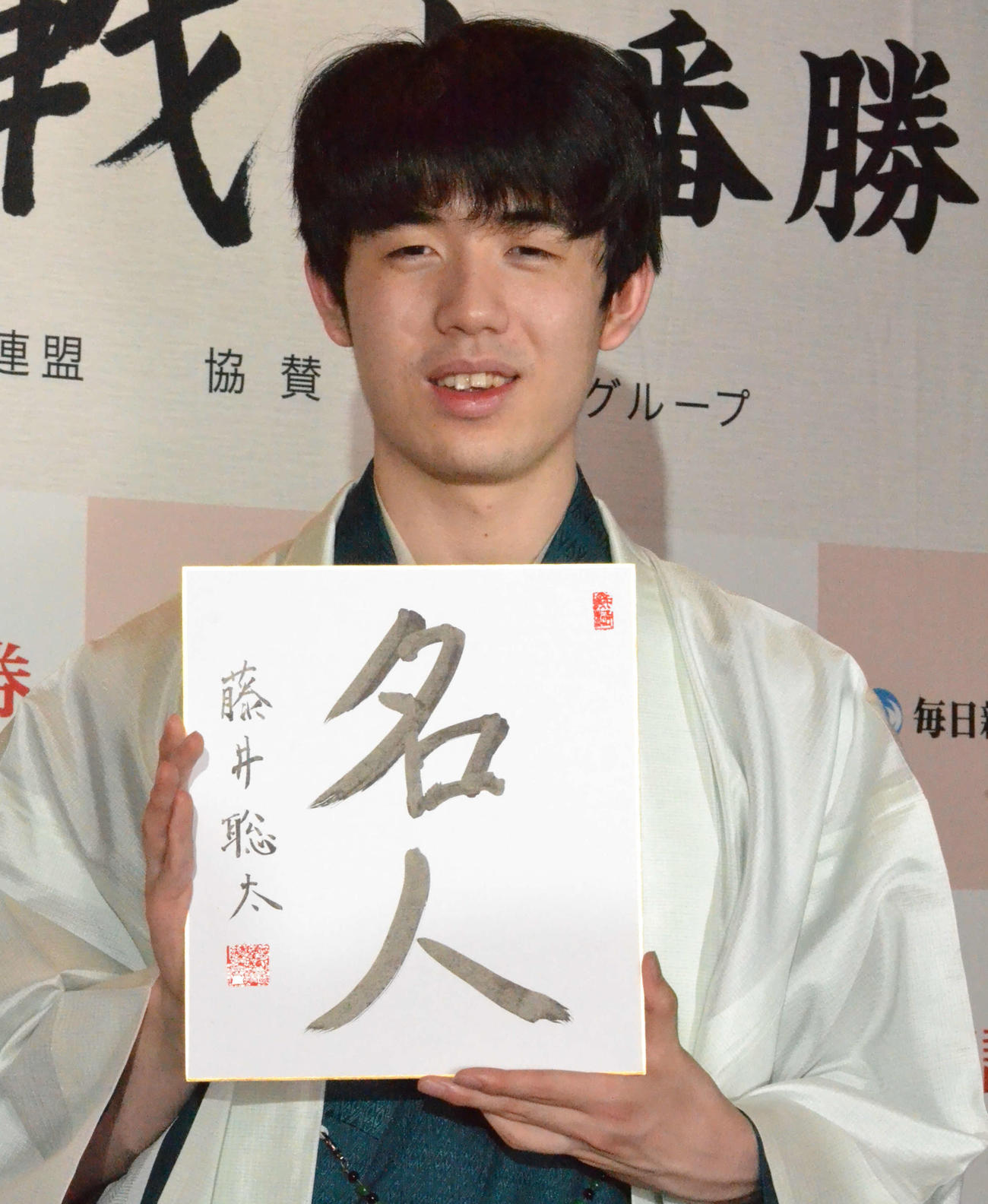 初仕事として「名人」と揮毫（きごう）した色紙を手に撮影に応じる藤井聡太新名人