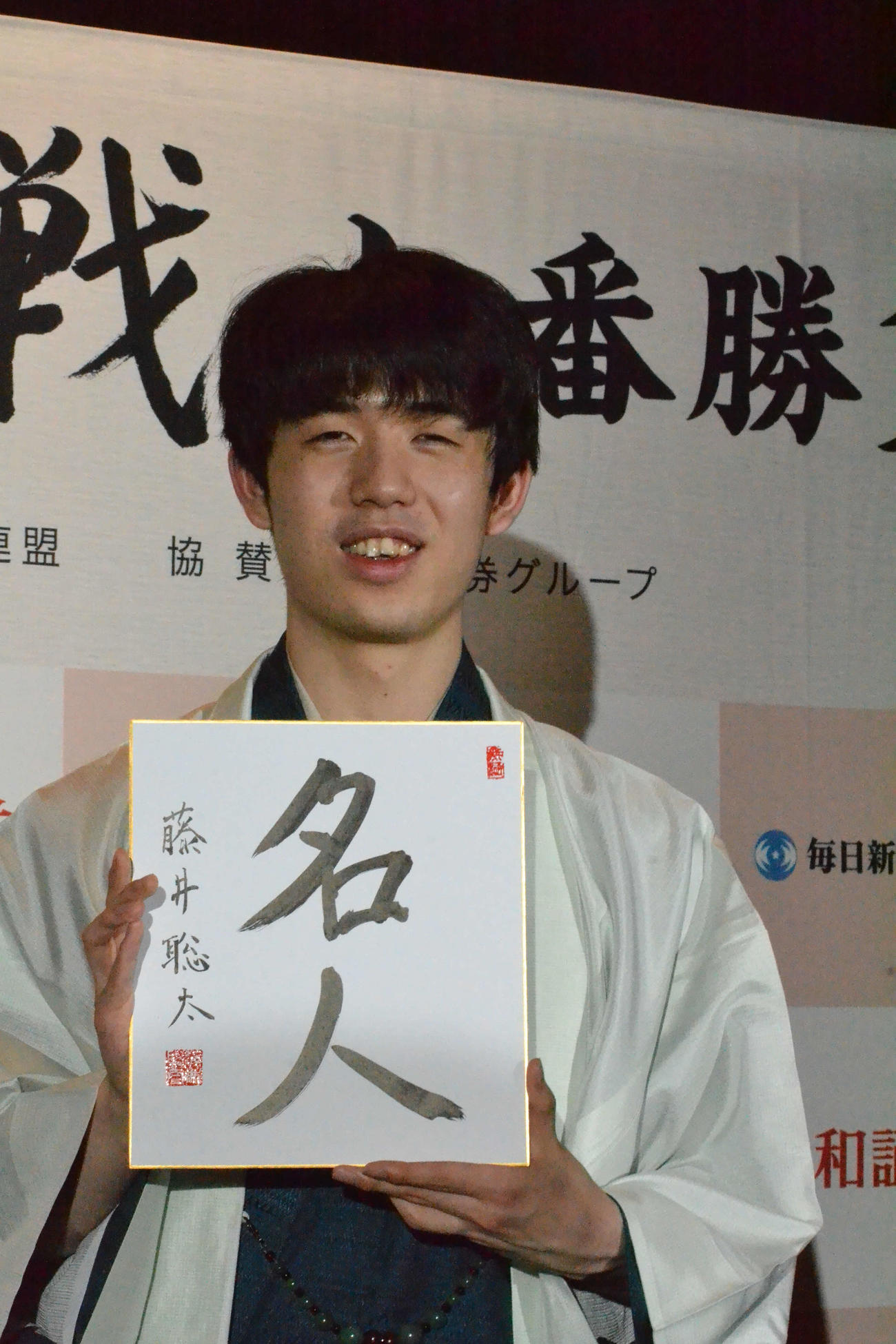 初仕事として「名人」と揮毫（きごう）した色紙を手に撮影に応じる藤井聡太新名人