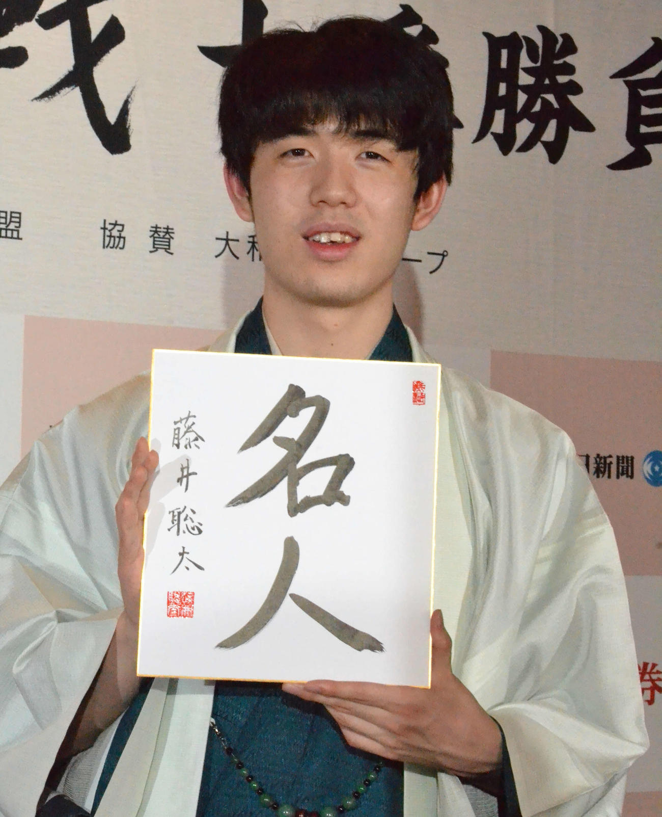 初仕事として「名人」と揮毫（きごう）した色紙を手に撮影に応じる藤井聡太新名人