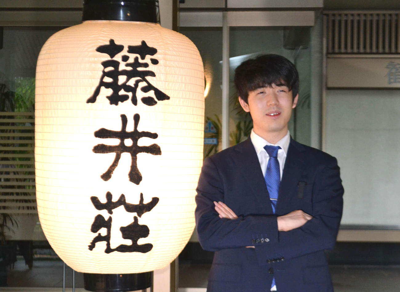 名人獲得から一夜明けて藤井荘のちょうちんの横で撮影に応じる藤井聡太名人