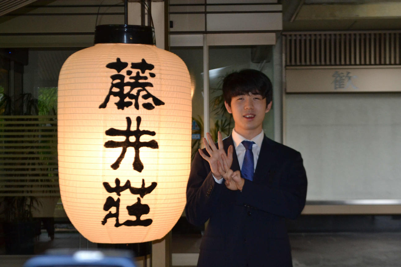 藤井荘のちょうちんの横で史上最年少7冠の「7」を表現する藤井聡太名人