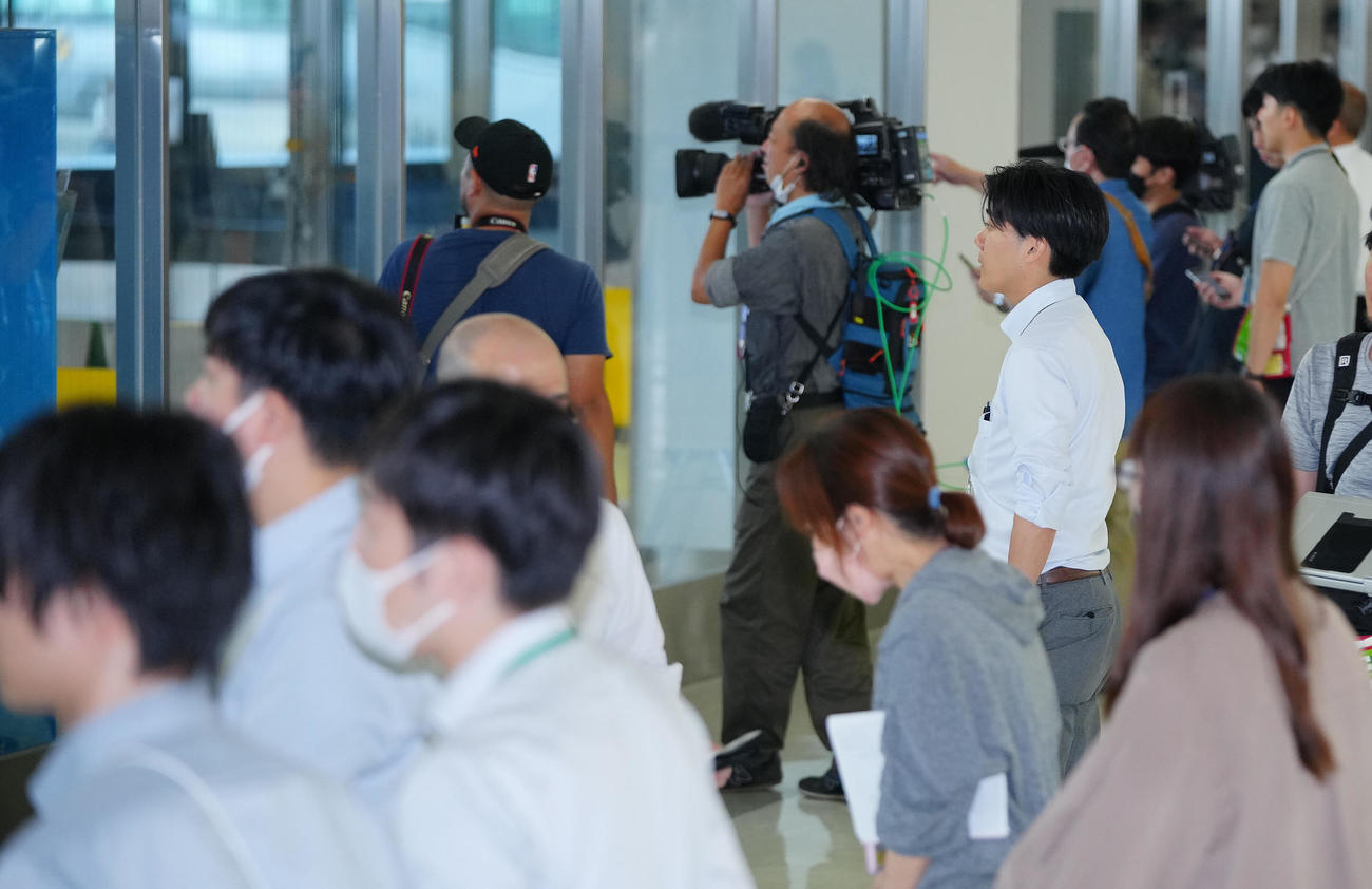 ガーシーこと東谷義和容疑者を乗せた飛行機が成田空港に着陸し窓の外に目を向ける多くの報道陣（撮影・垰建太）