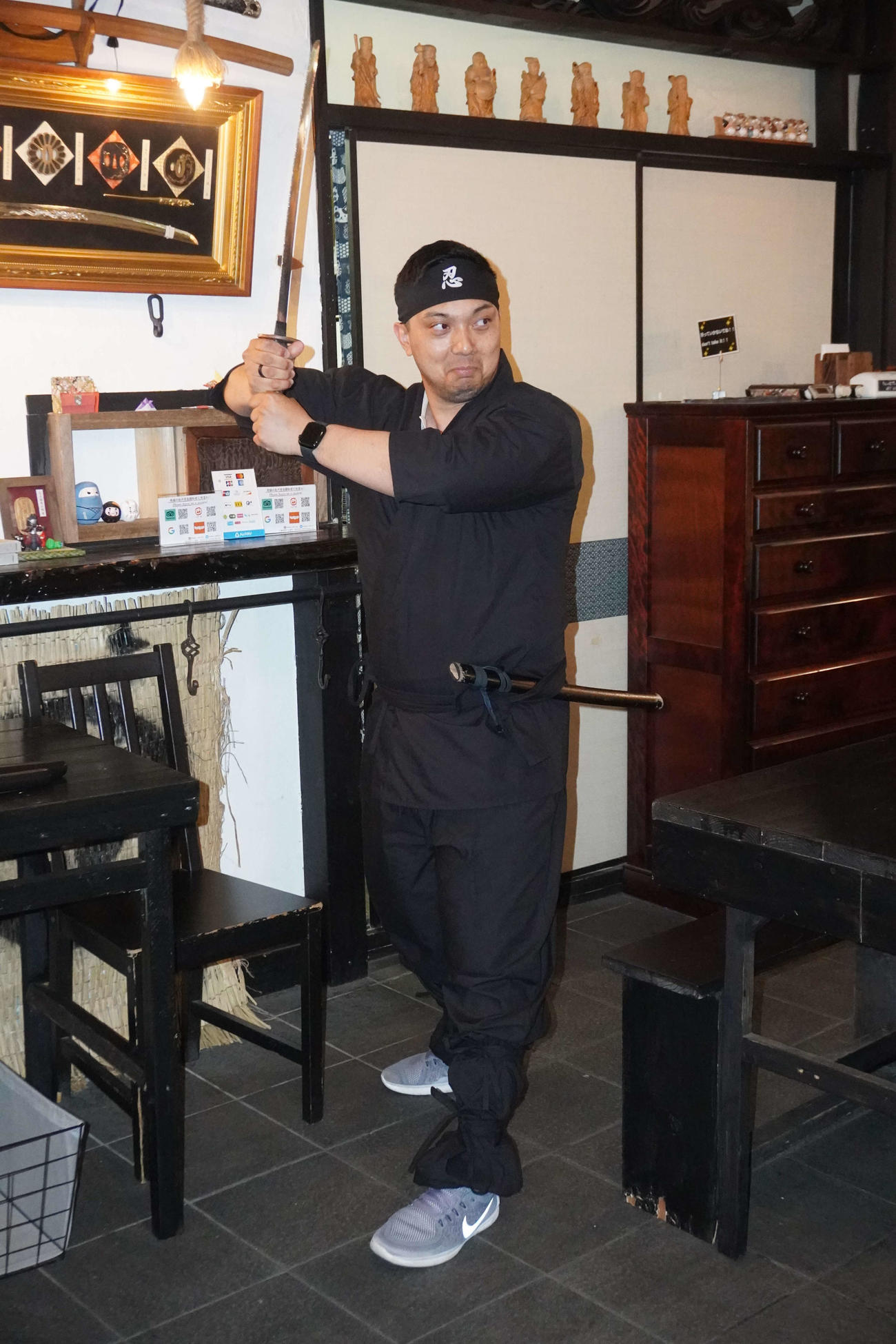 忍者カフェで刀を握りポーズをとるアーサーさん（撮影・沢田直人）