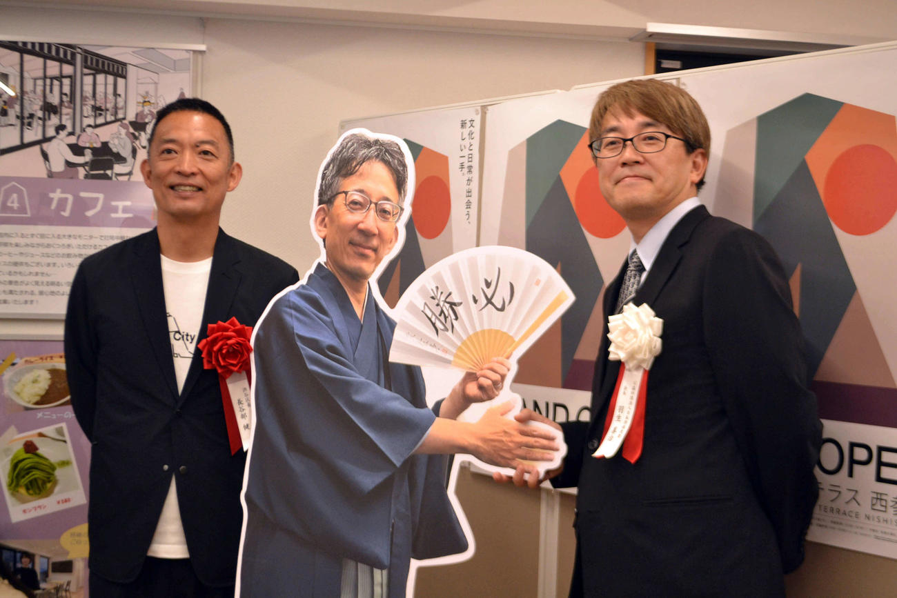 羽生会長（右）はギャラリーに展示された佐藤前会長の等身大パネルと新旧交代の握手を交わす。左は渋谷区の長谷部区長。（撮影・赤塚辰浩）